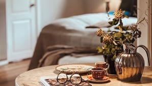 A cozy room with a bed, a table with a teapot, cups, and a vase with flowers. - The Woodland Lodge Gisselfeld (Haslev)