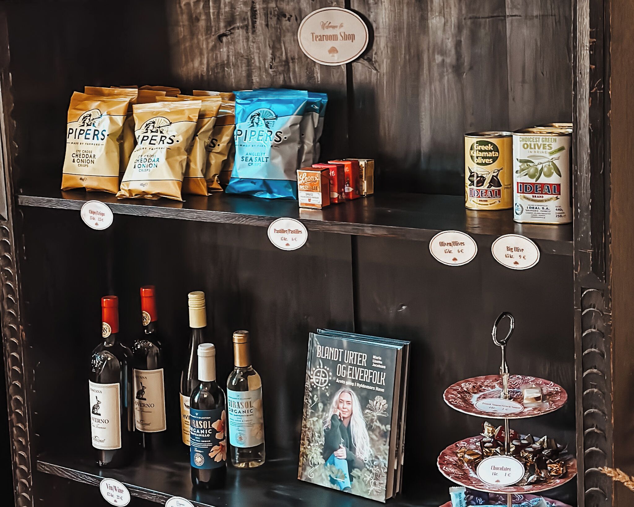 A selection of snacks, olive oil, and wine bottles on shelves.