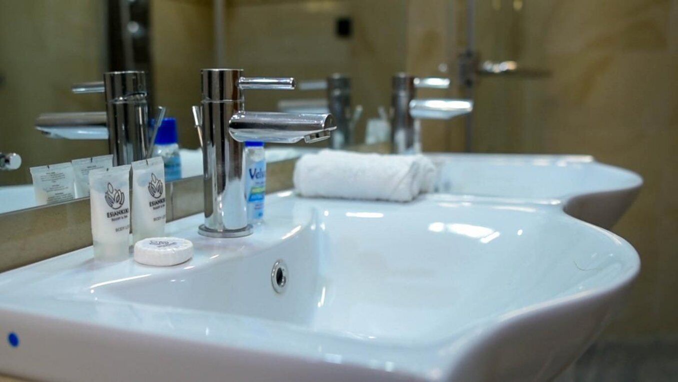A bathroom sink with a mirror, two faucets, and toiletries.