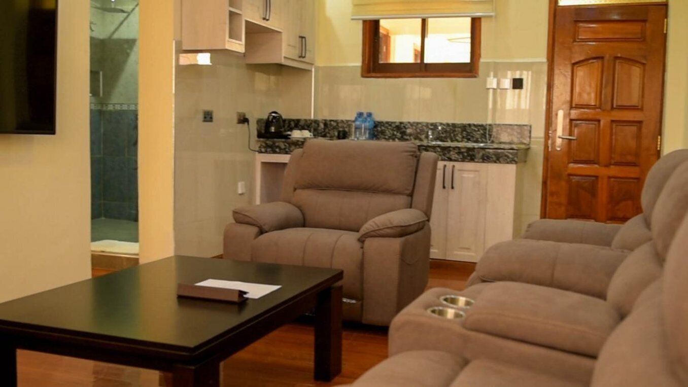 A living room with a sofa, a coffee table, and a kitchen area in the background.