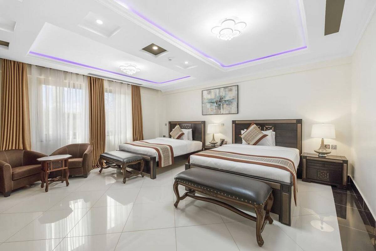 Una habitación de hotel con dos camas, un sofá, una mesita de café y un banco.