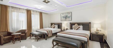 A hotel room with two beds, a sofa, a coffee table, and a bench.
