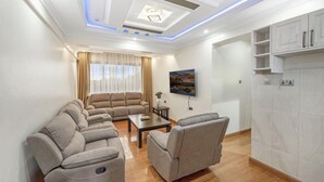 Ein modernes Wohnzimmer mit einem Ecksofa, einem Couchtisch und einem an der Wand montierten Fernseher.
