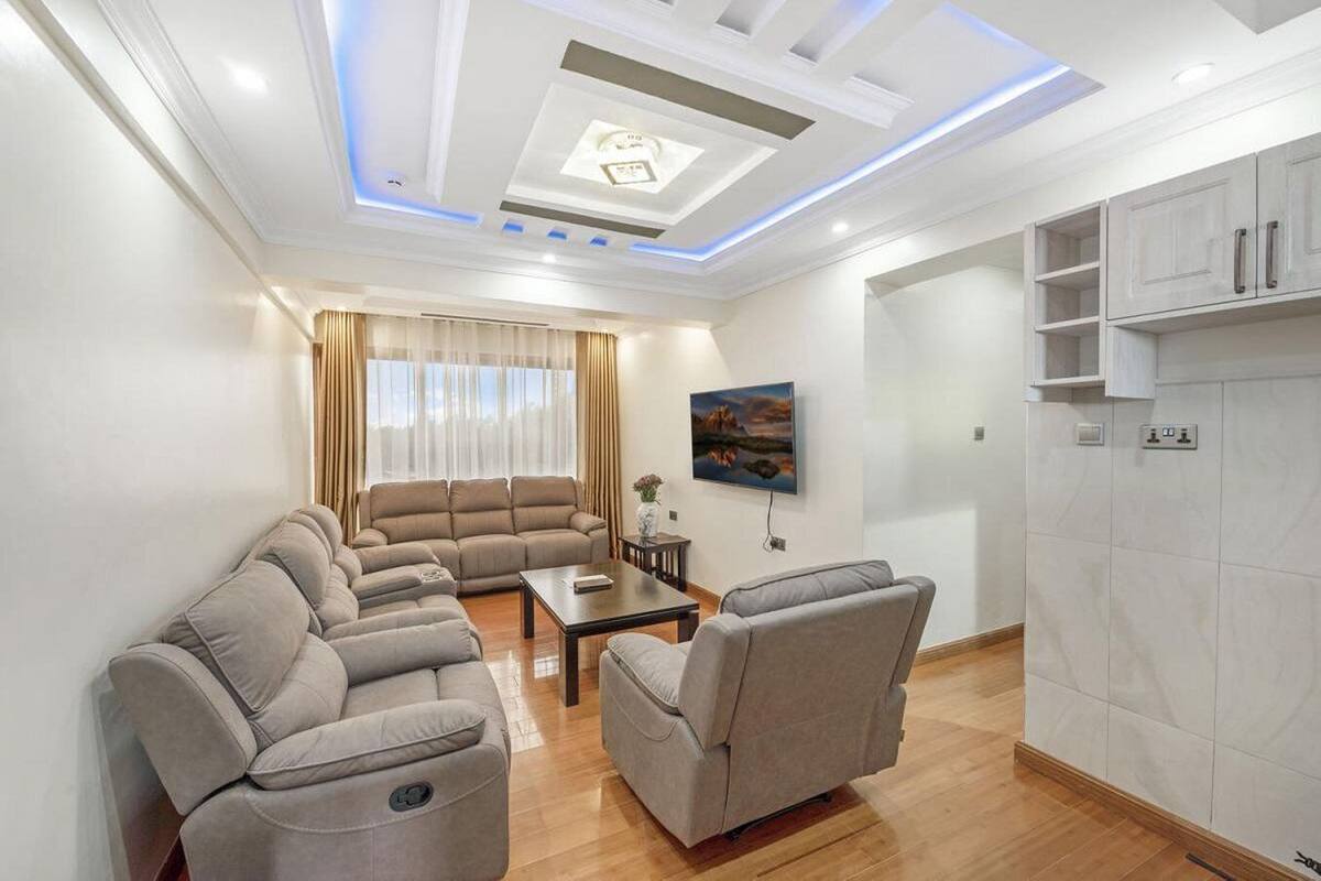 Una sala moderna con un sofá seccional, una mesa de centro y un televisor montado en la pared.