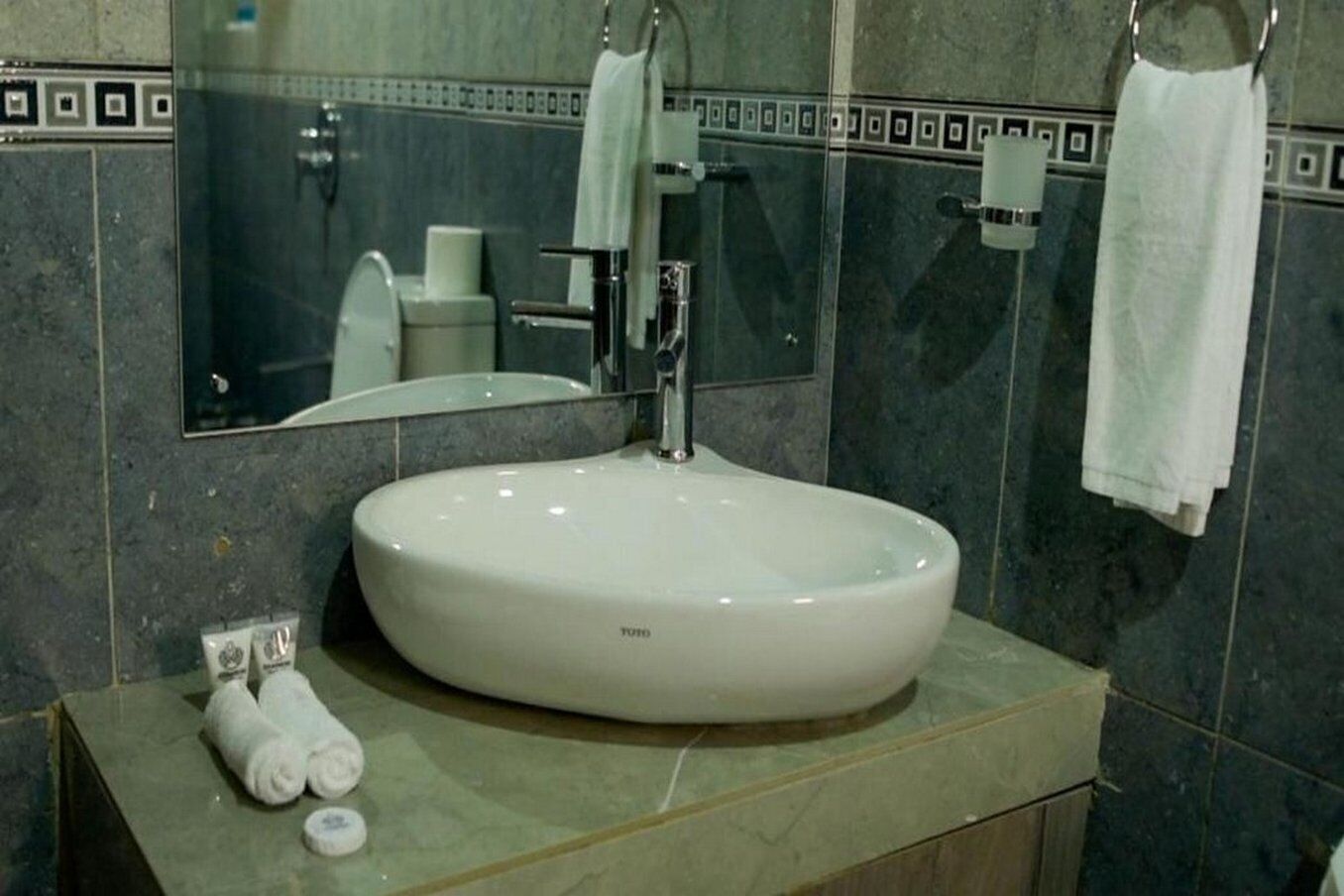 Ein Badezimmer mit einem runden weißen Waschbecken, einem Spiegel und zwei Handtüchern auf der Ablagefläche.