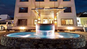 Ein modernes Gebäude mit einem zentralen Poolbereich, einer überdachten Sitzgelegenheit und einer Rezeption.