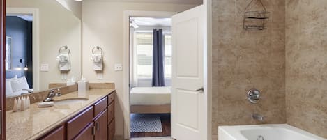 A modern bathroom with a large mirror, a bathtub, and a shower area.