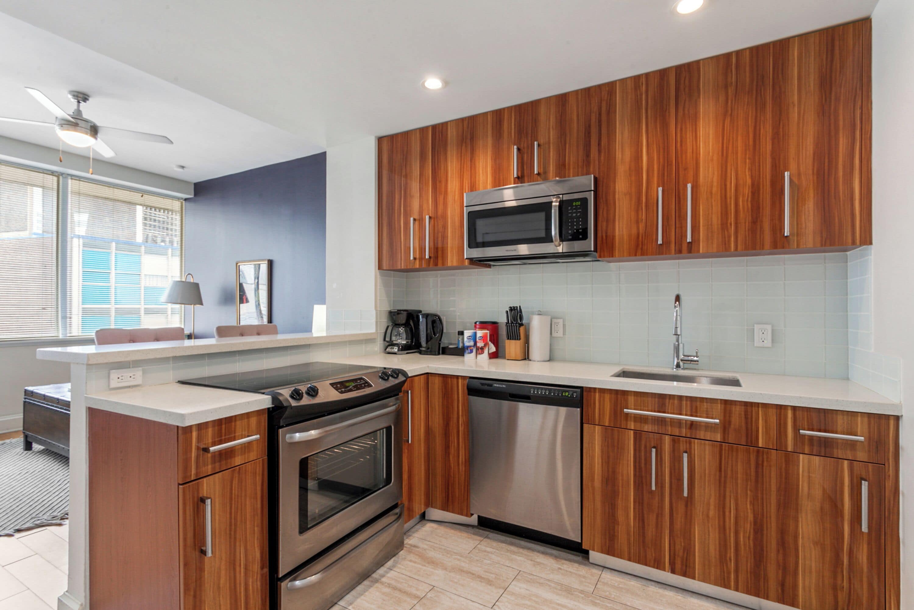 A modern kitchen with wooden cabinets, stainless steel appliances, and a white countertop.