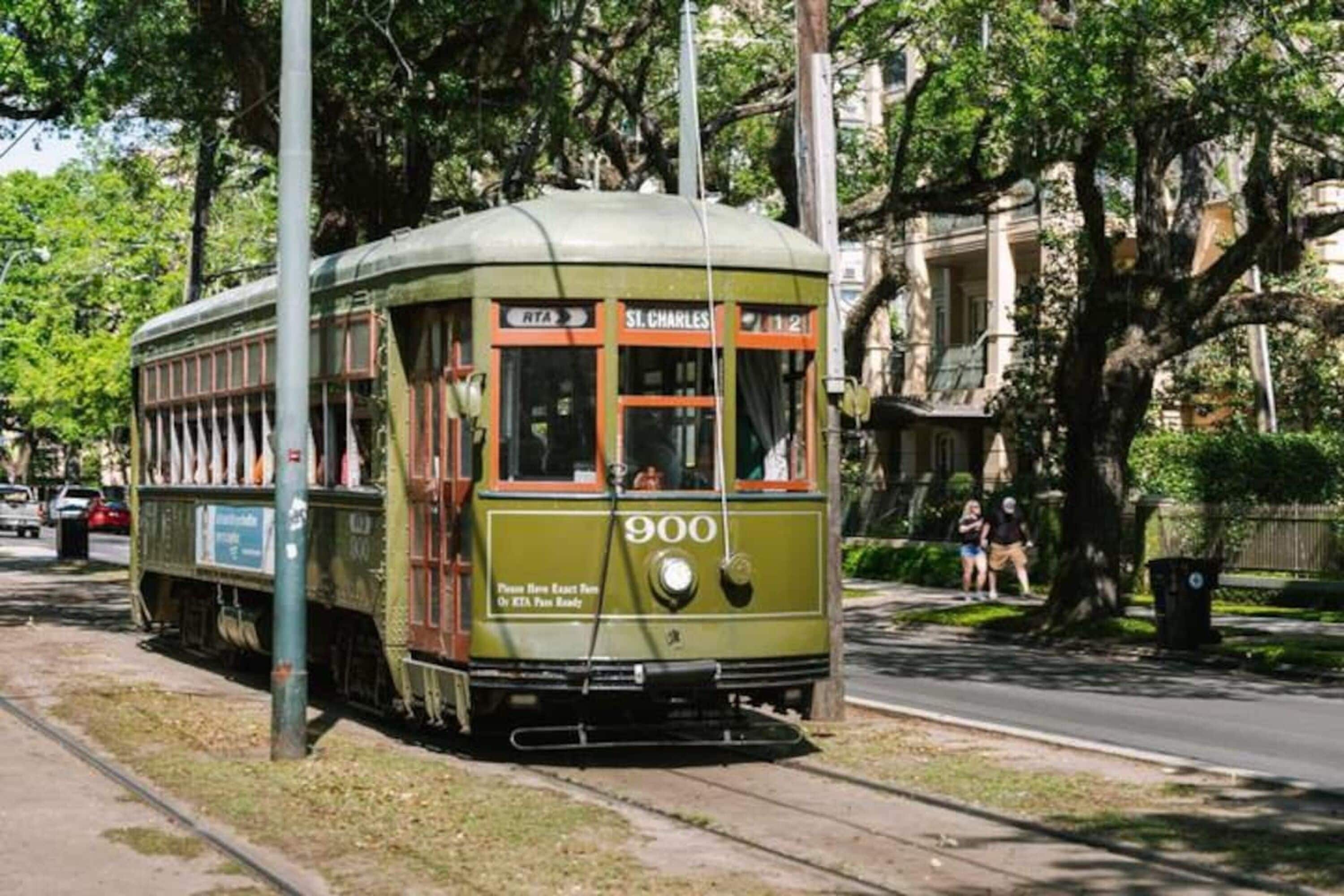 Un tranvía antiguo con el número 900, estacionado sobre una vía, con árboles y edificios al fondo.