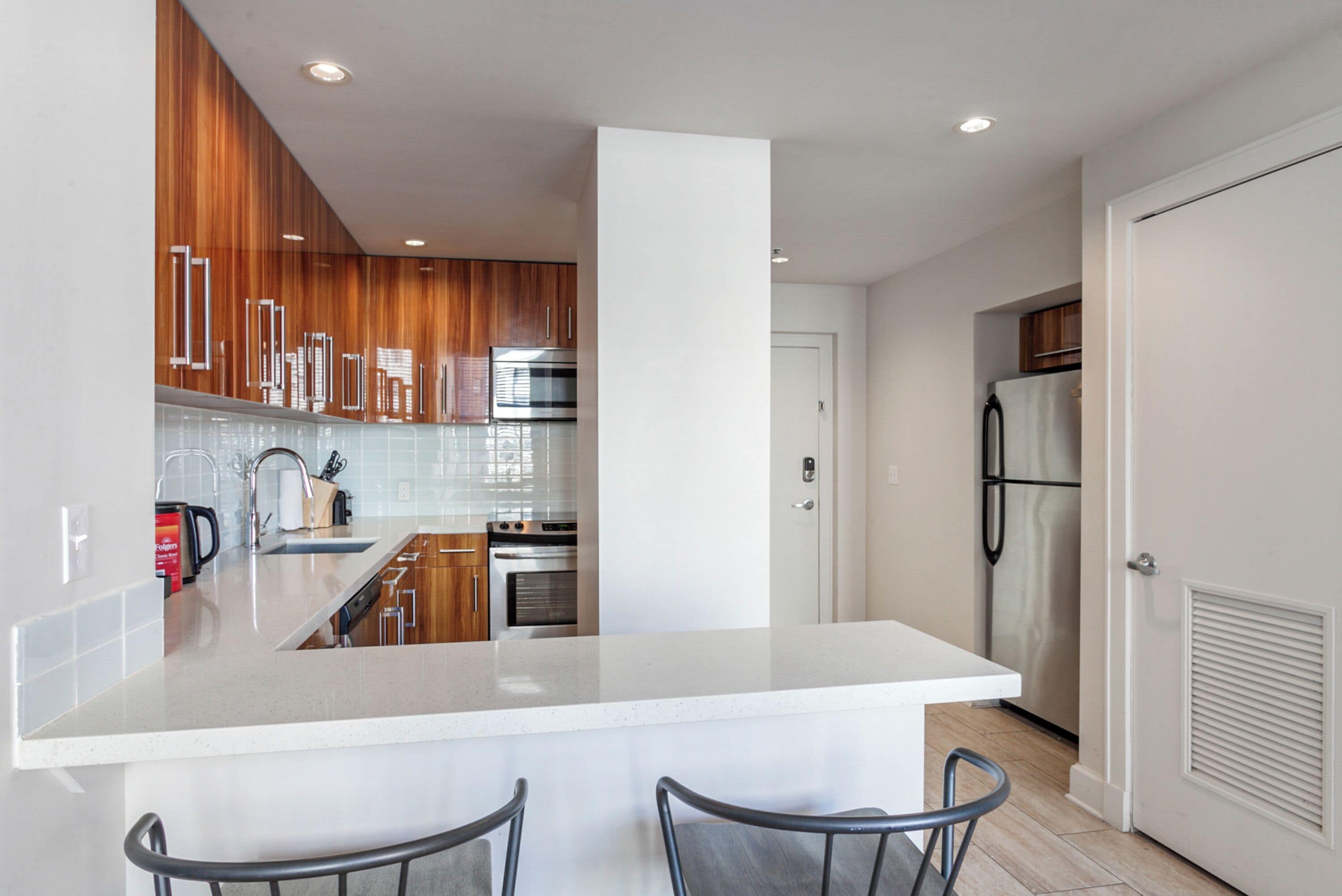 Una cocina moderna con una isla central, armarios de madera, electrodomésticos de acero inoxidable y una puerta blanca.