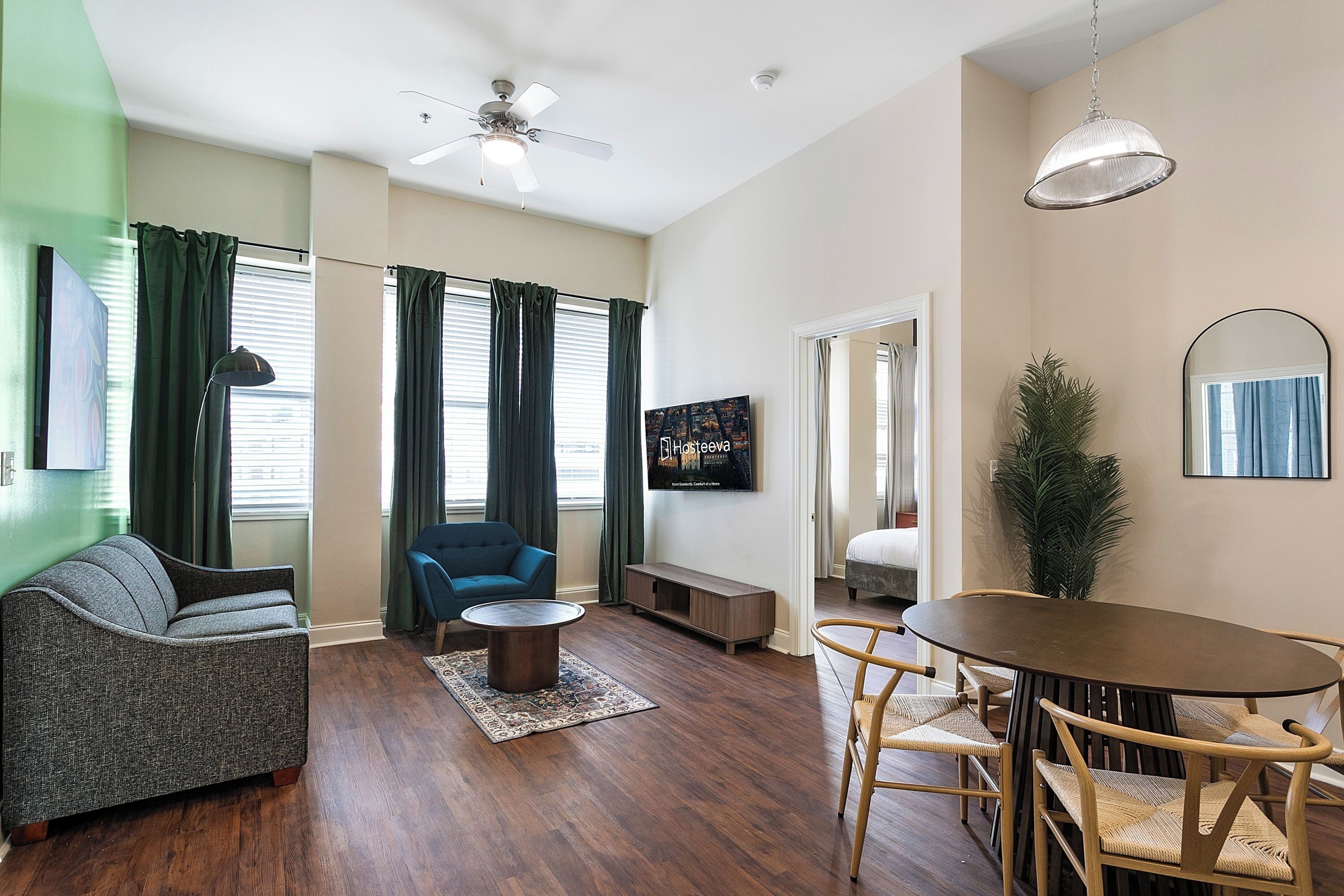 Una sala de estar moderna con un sofá, un sillón azul, una mesa de centro y una mesa de comedor con sillas.
