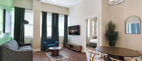 Una sala de estar moderna con un sofá, un sillón azul, una mesa de centro y una mesa de comedor con sillas.