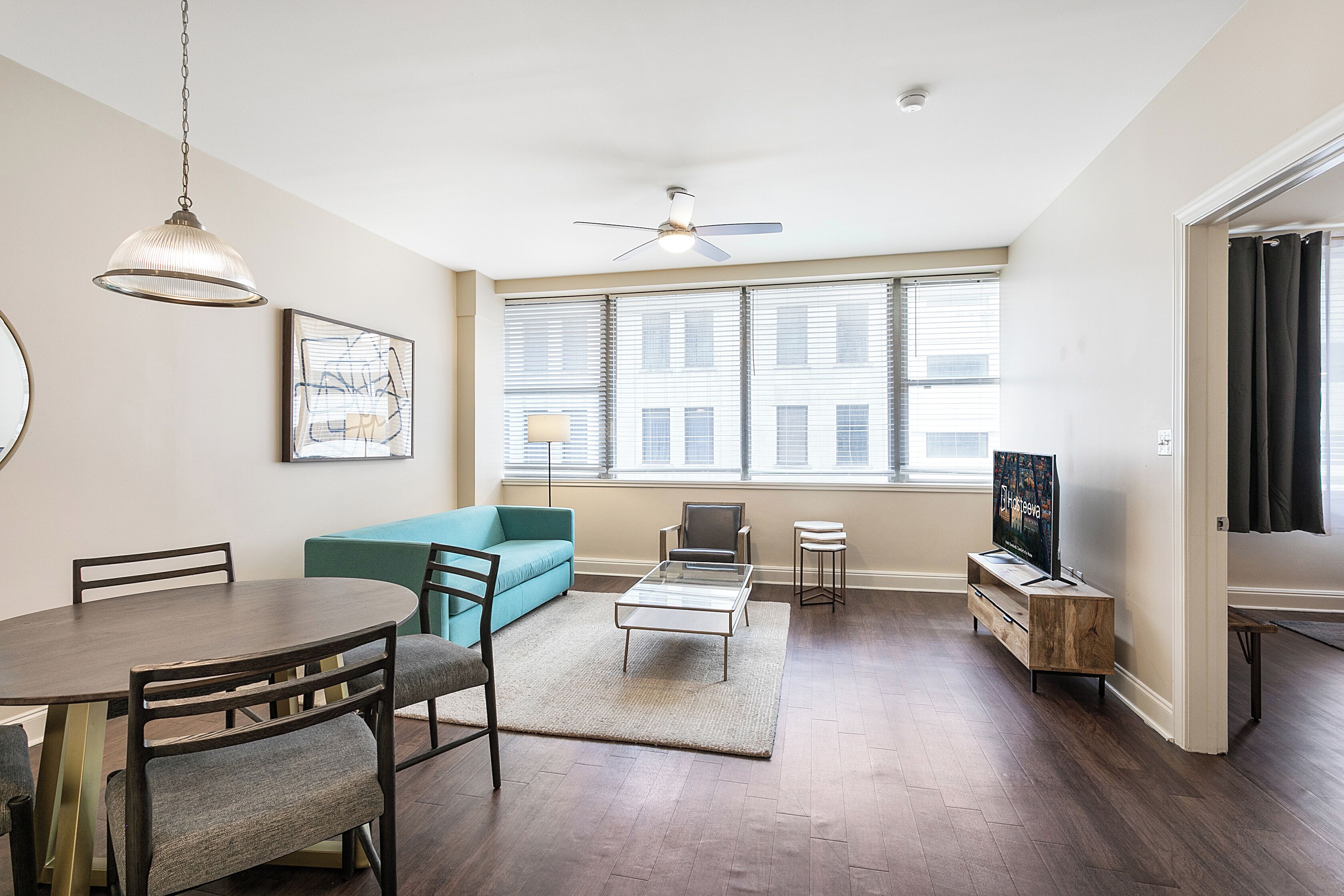 Un salon moderne comprenant une table à manger, un canapé, un téléviseur et un ventilateur de plafond.