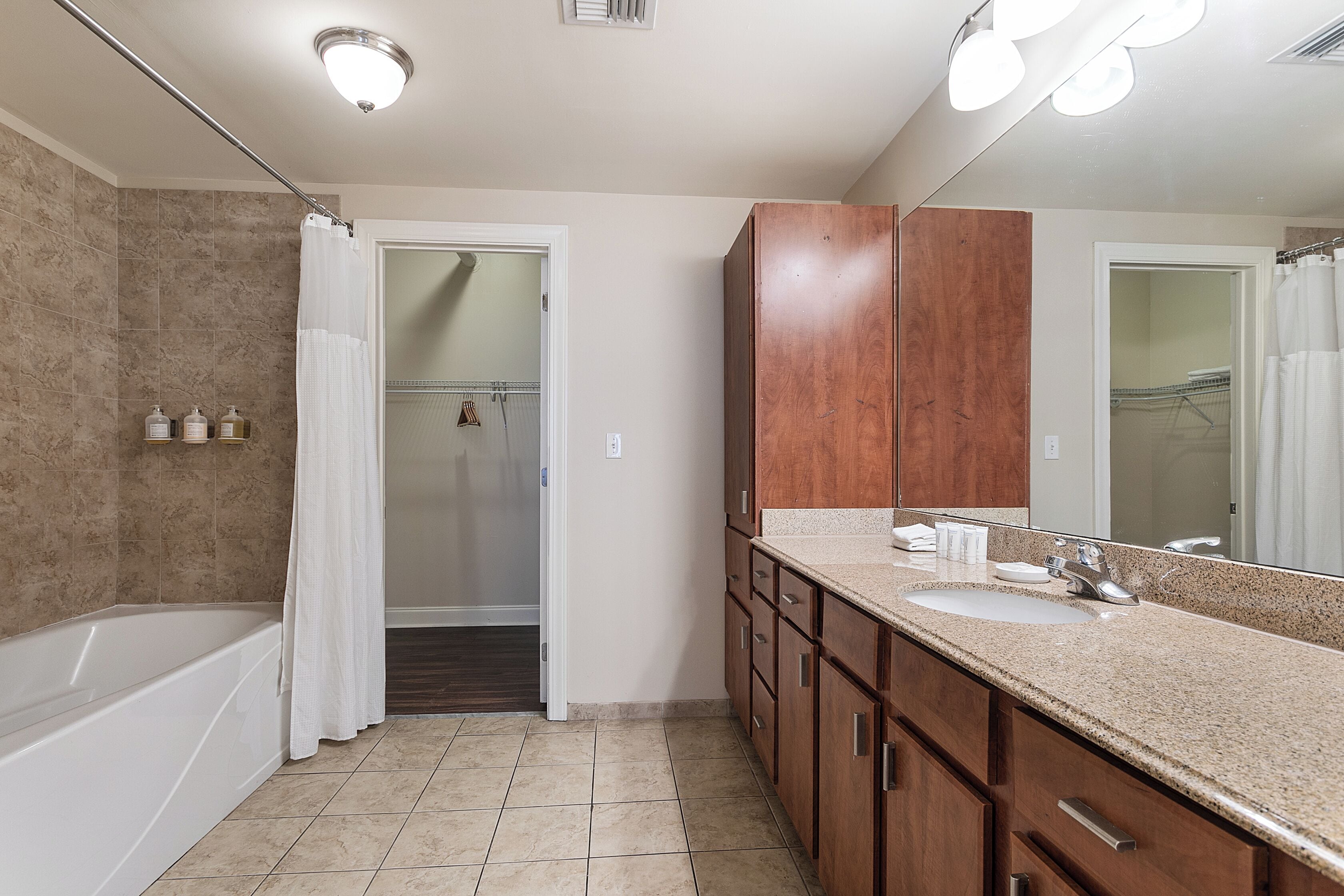 A bathroom with a bathtub, a sink, and a mirror.