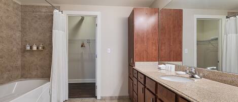 A bathroom with a bathtub, a sink, and a mirror.