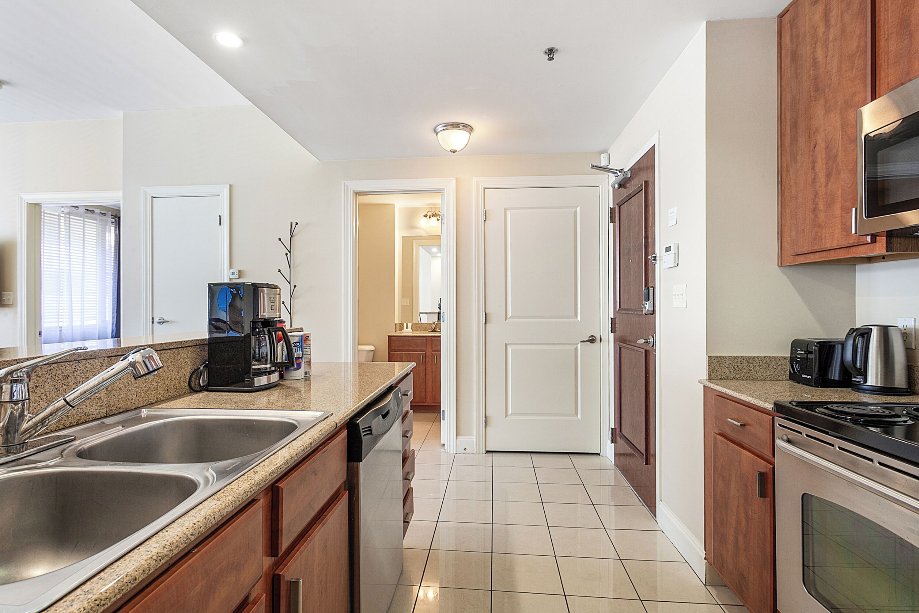 A modern kitchen with stainless steel appliances, wooden cabinets, and a tiled backsplash.
