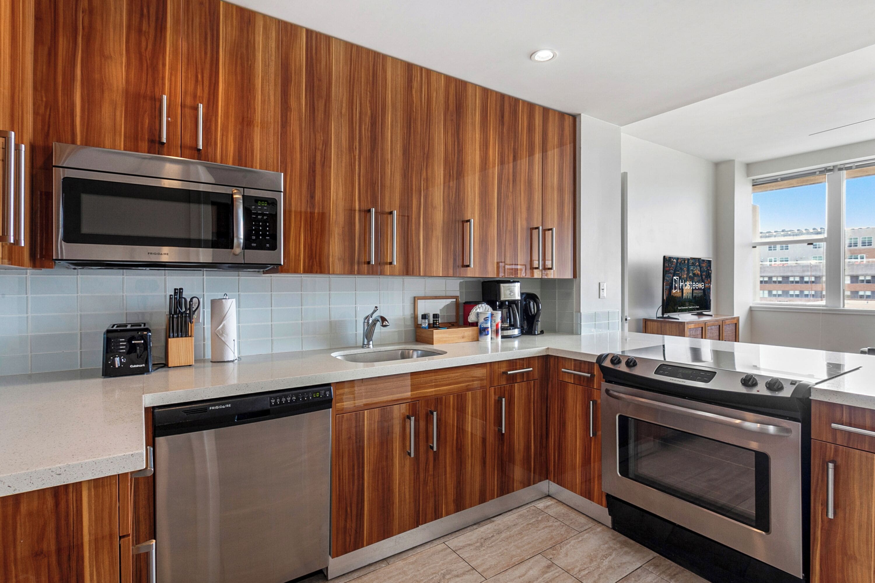 Une cuisine moderne avec des meubles en bois, des appareils électroménagers en acier inoxydable et un lave-vaisselle.