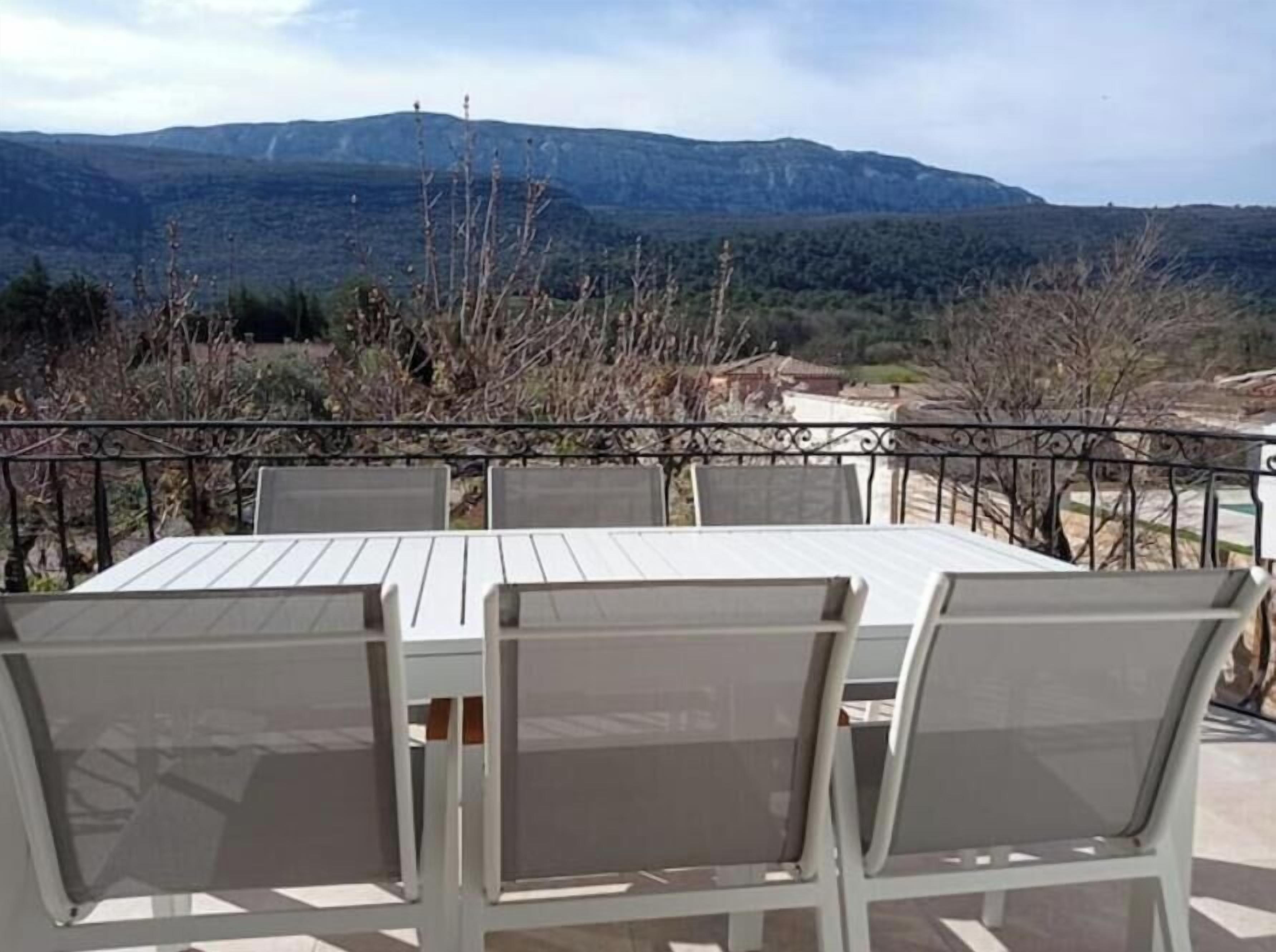 A dining area with a table and chairs, overlooking a mountainous landscape.