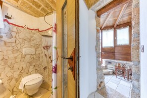 Une salle de bain avec un mur décoré de mosaïques, une porte en bois et une vue sur une terrasse en bois.