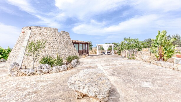 A stone courtyard with a large rock, a small building, and a pergola. - Country House 'Il Papavero Rosso - Cozy Villa' with Private garden and Wi-Fi (Gagliano del capo)