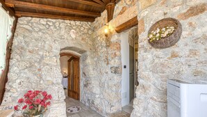 A stone-walled corridor with a wooden door, a wicker basket with flowers, and a white appliance. - Country House 'Il Papavero Rosso - Cozy Villa' with Private garden and Wi-Fi (Gagliano del capo)