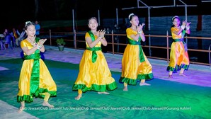 A group of dancers in traditional attire performing on a stage with a railing and potted plants in the background. - Club Jawai (Butwal)