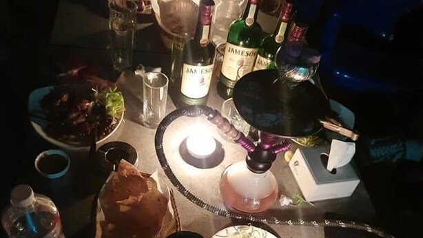 Una mesa dispuesta para una comida, con diversos platos, bebidas y una vela encendida.