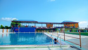 Una piscina con una plataforma de salto y una zona de estar cubierta.