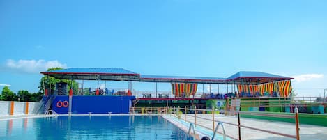 A swimming pool with a diving platform and a covered seating area.