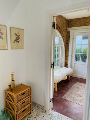 Une chambre avec un lit, une porte donnant sur un balcon et un mur orné d’illustrations botaniques encadrées.