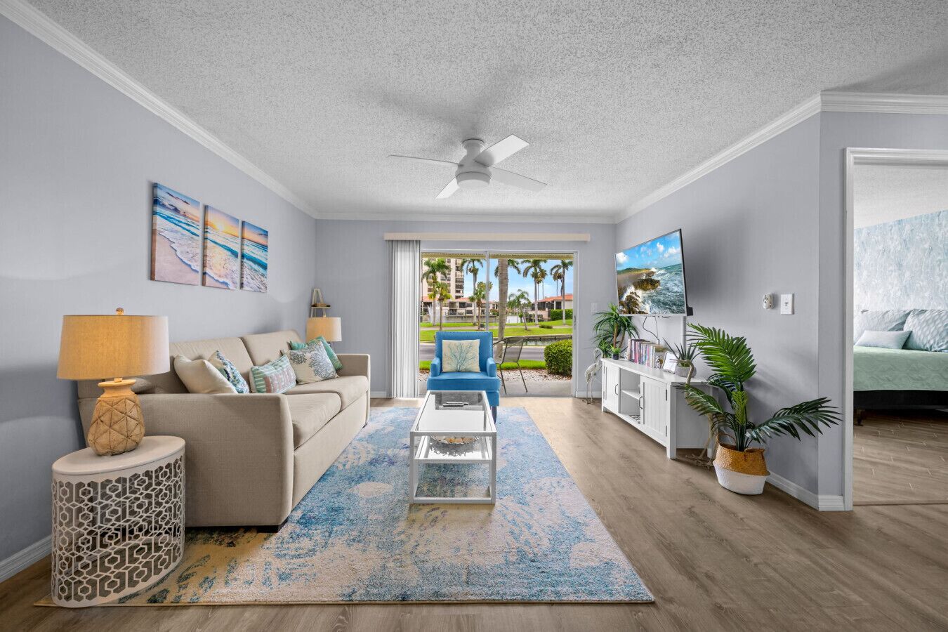 A living room with a sofa, coffee table, and a view of a tropical outdoor area.