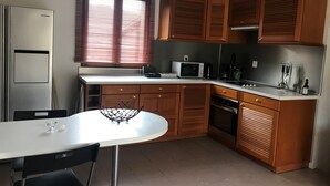 Keittiössä on puukuvioiset kaapit, valkoinen työtaso, mikroaaltouuni, vedenkeitin sekä pöytä ja tuolit.
