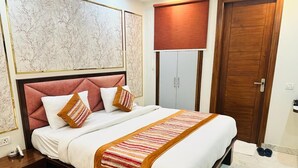 A neatly made bed with a striped blanket, a wooden headboard, and two pillows. - Hotel The Palm View (New Delhi)