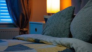 A neatly made bed with a quilt, a bedside lamp, and a nightstand with a lamp.