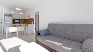 A modern living room with a grey sofa and a dining area with a white table and chairs. - Cozy apartment in Orihuela with WiFi (Orihuela)