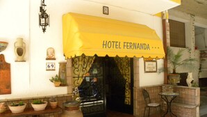 L’entrée d’un hôtel, surmontée d’un auvent jaune portant l’inscription « HÔTEL FERNANDA ».