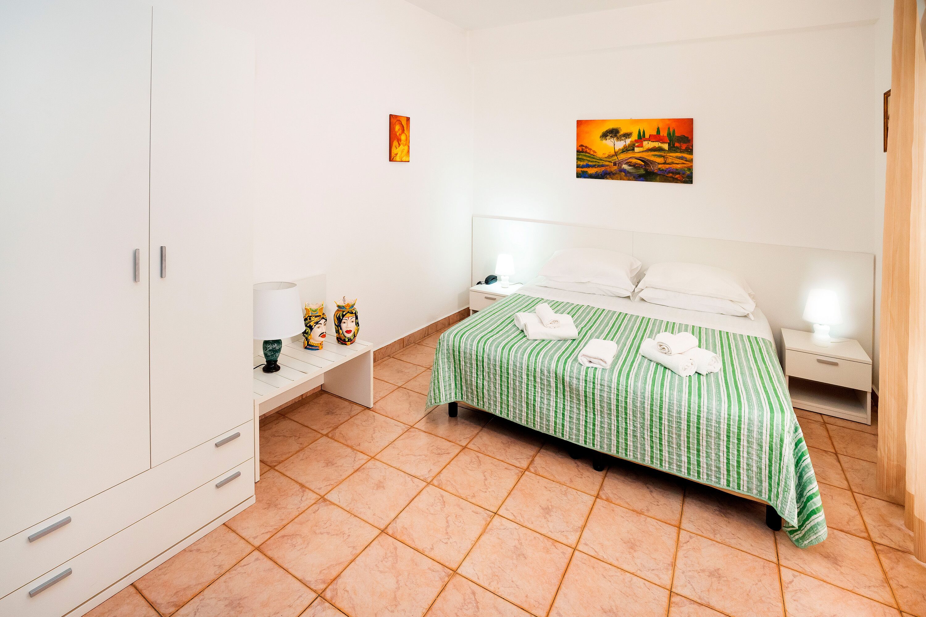 Un dormitorio ordenado con cama, mesitas de noche y armario.