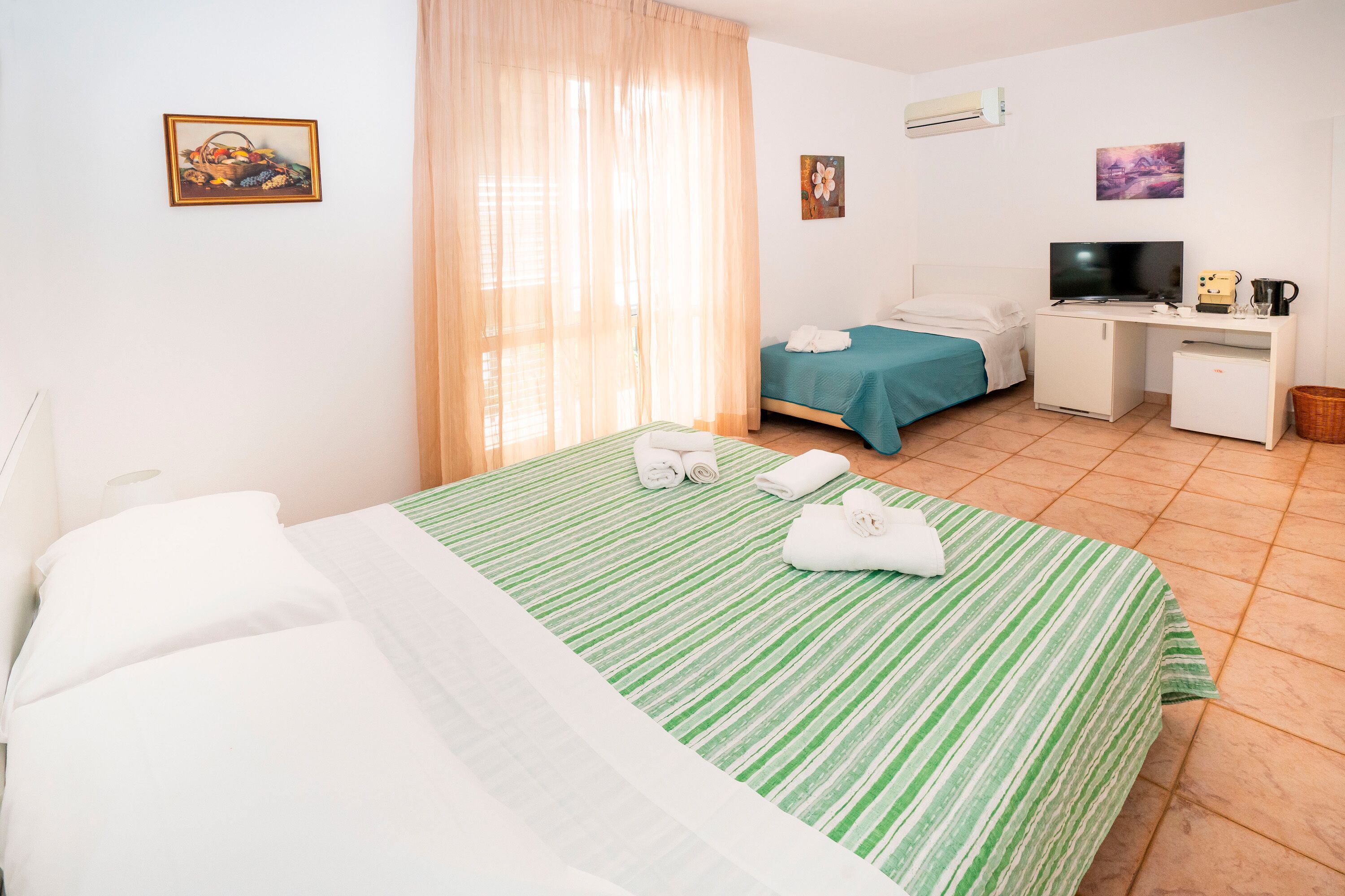 A hotel room with a bed, a desk, a television, and a small refrigerator.