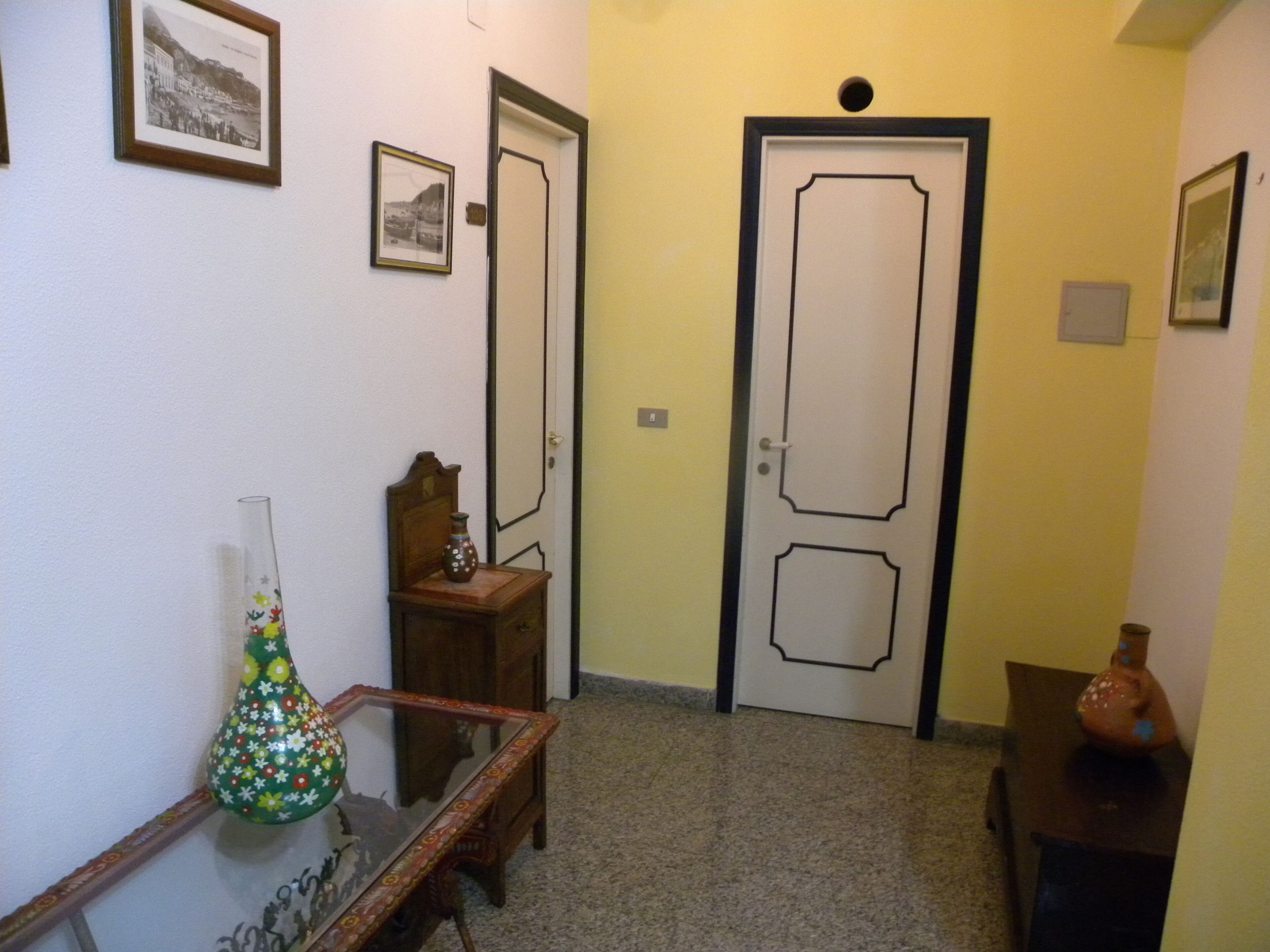 Un pasillo con un banco de madera, un jarrón y una puerta de diseño sencillo.