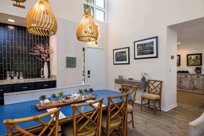 Une cuisine moderne avec un îlot central bleu, des chaises en osier et des luminaires suspendus.