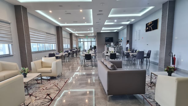 A spacious hotel lobby with modern furnishings, a central seating area, and a kitchen in the background. - Sami Court Airport Hotel Abuja (Abuja)
