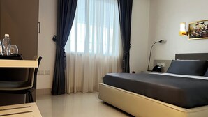 A hotel room with a bed, a desk, a chair, a lamp, and a window with curtains. - Sami Court Airport Hotel Abuja (Abuja)