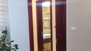 A hotel room with a wooden door, a small potted plant, and a sign above the door reading "ABUJA". - Sami Court Airport Hotel Abuja (Abuja)