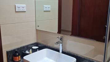 A bathroom with a white sink, a mirror, and a wooden door.