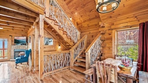 Un interior de madera con una escalera, una chimenea y un comedor.