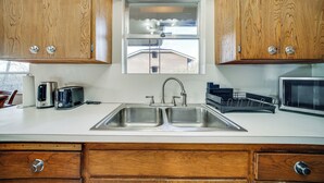A kitchen with wooden cabinets, a double sink, a window with a view, and a microwave. - Quaint Renton Home ~ 15 Mi to Downtown Seattle! (Renton)