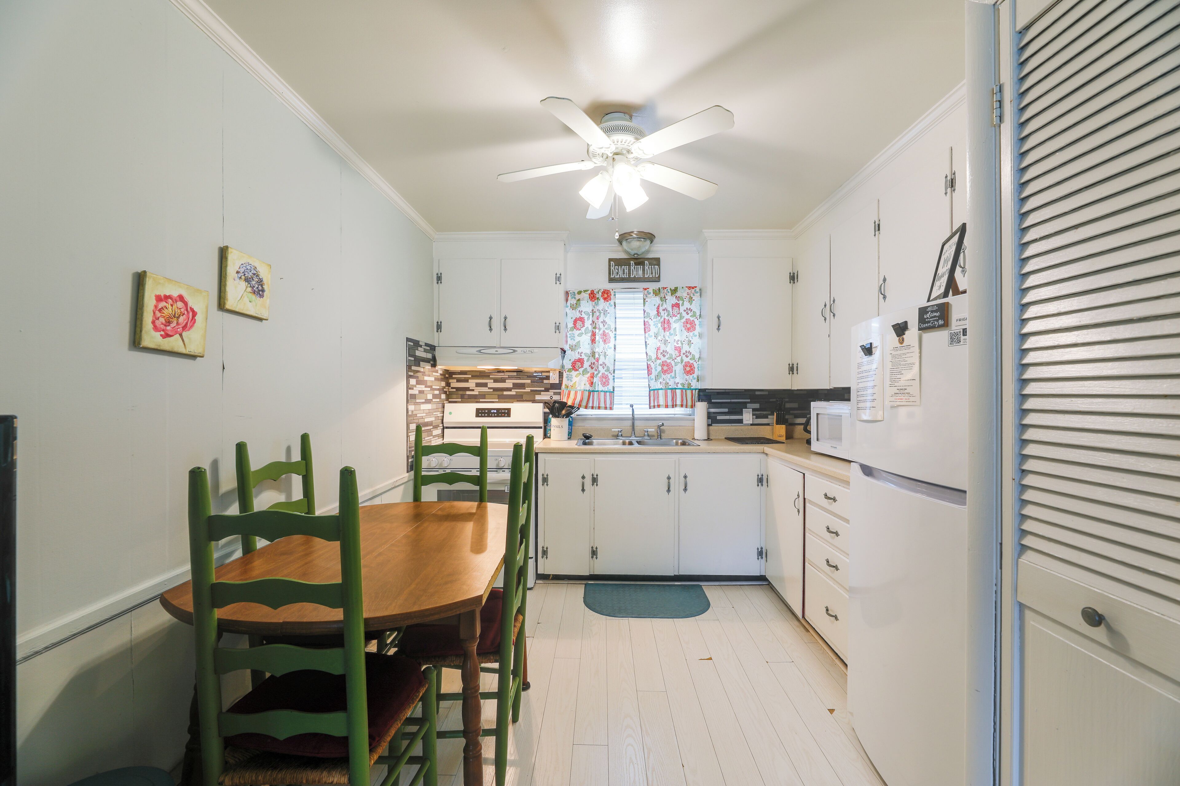Una cocina con armarios blancos, una mesa de comedor de madera y sillas.