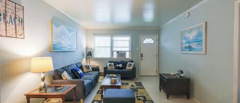 A living room with a sofa, a coffee table, a lamp, and a rug.