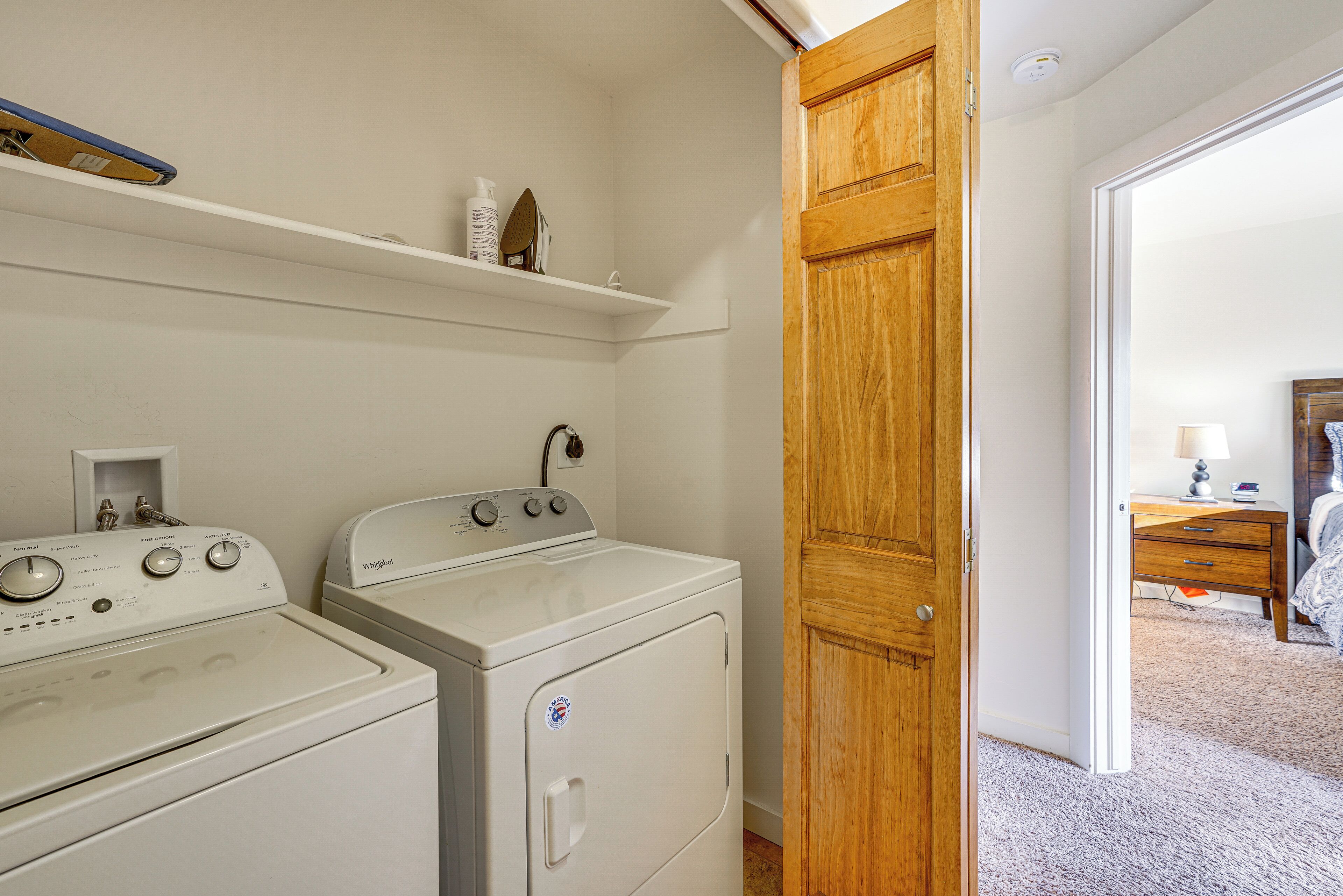 A laundry area with two white washers and dryers, a wooden door, and a shelf above the dryers.