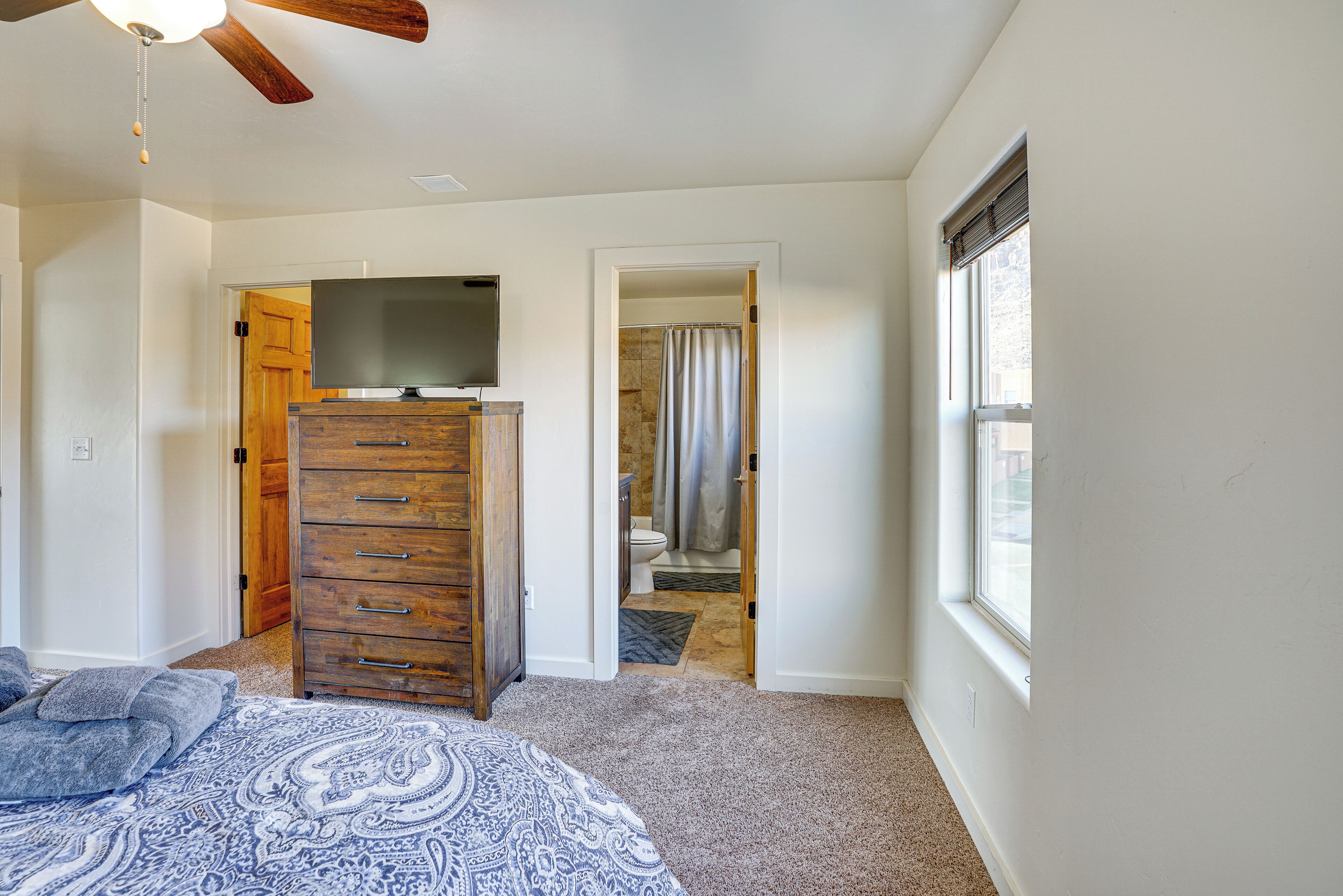 A bedroom with a bed, a dresser, a TV, and a window.